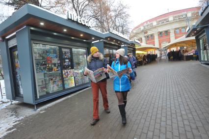 Москва.  Молодые люди  с газетой  `Комсомольская правда` у обновленного  киоска `Пресса` у метро Краснопресненская.