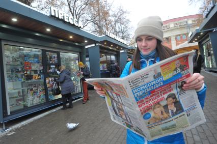 Москва.  Девушка  с газетой  `Комсомольская правда` у обновленного  киоска `Пресса` у метро Краснопресненская.