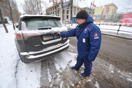 Москва. Пеший инспектор `Администрации московского парковочного пространства` проверяет оплату парковки.