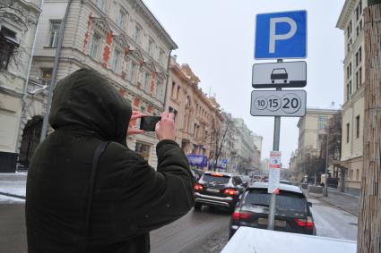 Москва. Мужчина фотографирует информационный знак с новыми тарифами на платную парковку в центре города. Со 2 декабря 2016 года тариф на платную парковку изменится на 732 улицах Москвы и будет составлять от 50 рублей за первые полчаса до 200 рублей в час.