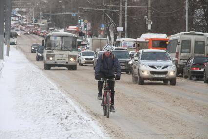 Нижний Новгород. Велосипедист едет по автомобильной дороге на одной из улиц города.