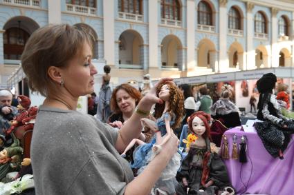 Москва.  Женщина с куклой в руках на VII Московской международной выставке `Искусство куклы` в Гостином дворе.