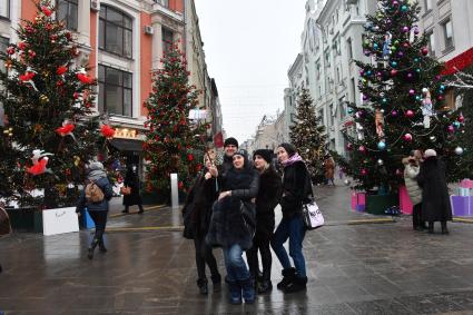 Москва. Молодые люди фотографируются у новогодних елей на одной из улиц города.