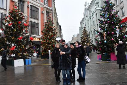 Москва. Молодые люди фотографируются у новогодних елей на одной из улиц города.