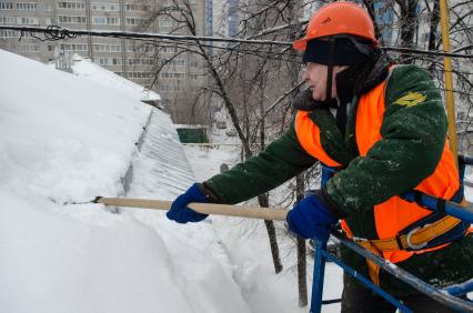 Самара. Сотрудник коммунальной службы счищает снег с крыши дома.