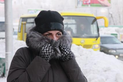Барнаул. Девушка на улице  закрывает лицо от холода.