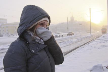 Барнаул. Девушка на улице  закрывает лицо от холода.