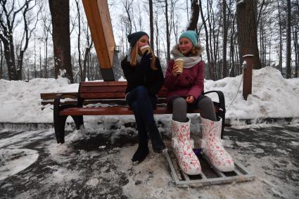 Москва. Девочка греет  ноги в термоваленках, которые установили в парке `Сокольники`на Аллее арок.