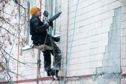 Нижний Новгород. Промышленный альпинист ремонтирует фасад жилого дома.