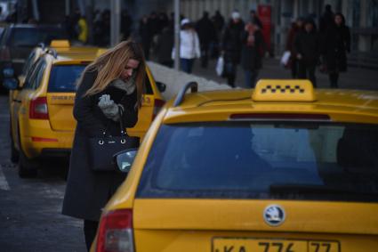 Москва. Девушка останавливает такси на улице города.