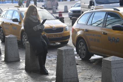 Москва. Девушка вызывает такси при помощи приложения, установленного в планшете.