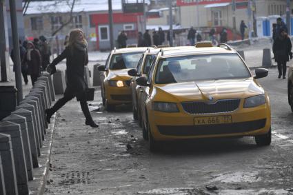 Москва. Девушка идет к автомобилям такси.