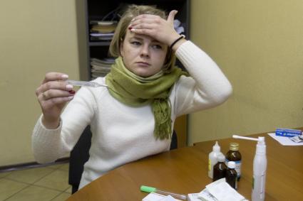 Иркутск. Девушка на рабочем месте в офисе измеряет температуру.