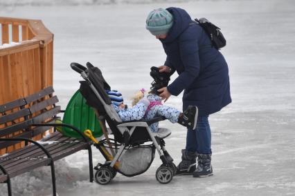 Москва.  Женщина  одевает коньки ребенку  на Чистых прудах.