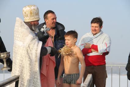 Уфа.  Священнослужитель окропляет святой водой мальчика во время крещенского купания.