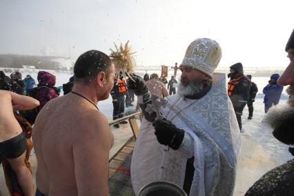 Уфа.  Священнослужитель окропляет святой водой верующего во время крещенского купания.