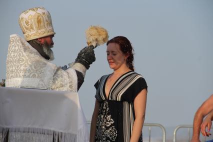 Уфа.  Священнослужитель окропляет святой водой верующую во время крещенского купания.