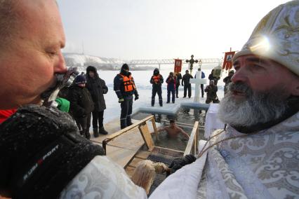 Уфа.  Священнослужитель окропляет святой водой верующего во время крещенского купания.