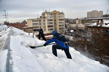 Новосибирск. Дворники на крыше лопатой счищают снег.