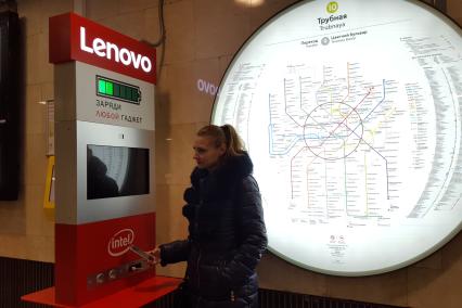 Москва. Девушка у стойки для зарядки гаджета в вестибюле метро Трубная.