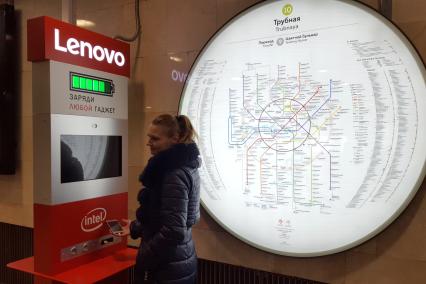 Москва. Девушка у стойки  для зарядки гаджета в вестибюле метро Трубная.