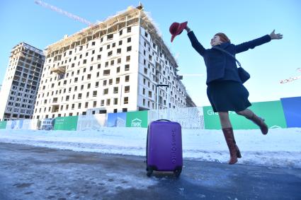 Москва.  Девушка с чемоданом  рядом с новостройкой.