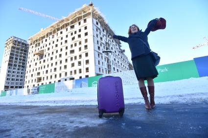 Москва.  Девушка с чемоданом  рядом с новостройкой.