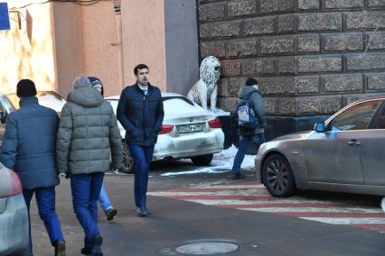 Москва.  Мужчина и `Зевающий `лев  у ворот на Гончарной улице.