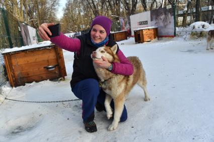 Москва. Девушка фотографируется  с собакой породы хаски в парке `Сокольники` , где проходит  реабилитационно-образовательная программа `По пути с хаски`.