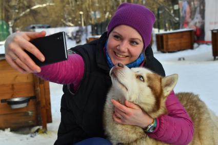 Москва. Девушка фотографируется  с собакой породы хаски в парке `Сокольники` , где проходит  реабилитационно-образовательная программа `По пути с хаски`.