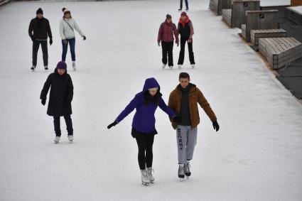 Москва.  Молодые люди катаются на катке в Парке Горького.