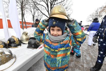 Москва. Мальчик примеряет каску  во время  Всероссийского пожарно-спасательного флешмоба  на катке в парке Горького .