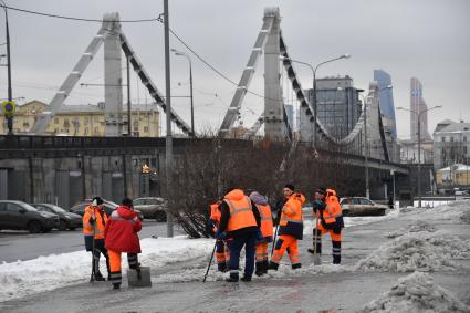 Москва. Сотрудники коммунальных служб очищают тротуар от снега у Крымского моста.