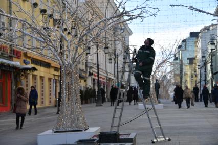 Москва. Работник коммунальных служб проверяет гирлянды в Камергерском переулке.