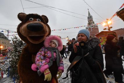 Москва. Ростовая кукла Медведь держит девочку на Красной площади во время масленичных гуляний.