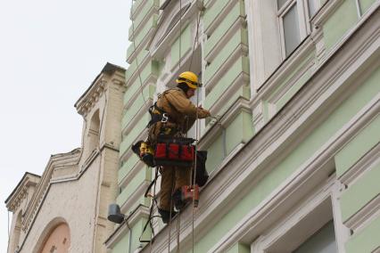 Москва. Промышленный альпинист ремонтирует фасад здания.