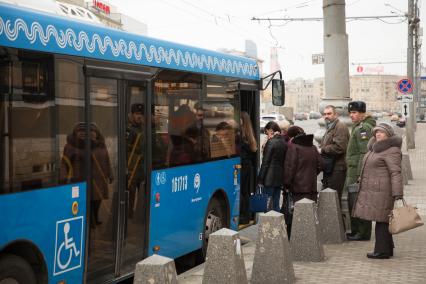 Москва.  Пассажиры садятся в автобус на остановке общественного транспорта.