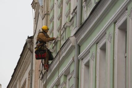 Москва. Промышленный альпинист ремонтирует фасад здания.