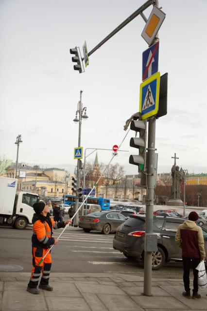 Москва. Сотрудник коммунальной службы моет дорожный знак на одной из улиц города.