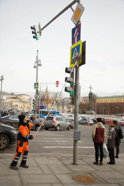 Москва. Сотрудник коммунальной службы моет дорожный знак на одной из улиц города.