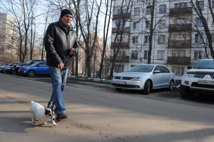 Москва.  Мужчина гуляет с собакой  во дворе жилого пятиэтажного дома в районе Матвеевское.