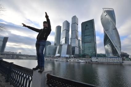 Москва.  Молодой человек позирует на фоне Делового центра  Москва-Сити  на набережной Тараса Шевченко.