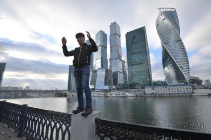 Москва.  Молодой человек позирует на фоне Делового центра  Москва-Сити  на набережной Тараса Шевченко.