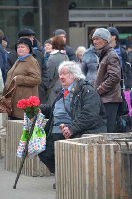 Москва. Пожилой мужчина с искусственными цветами возле станции метро Шаболовская.