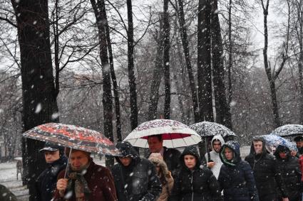 Москва. Люди идут по парку в снегопад.