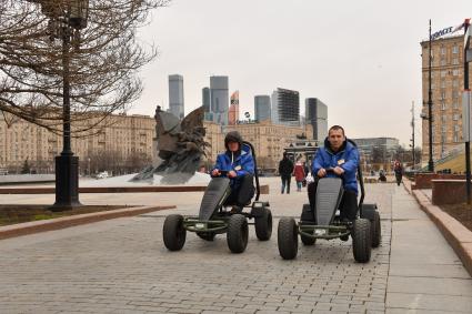 Москва. Сотрудники проката едут на веломобилях в парке Победы