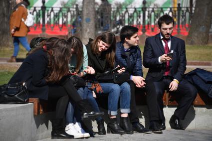 Москва. Молодые люди сидят на скамейке на бульваре.