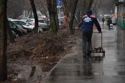 Москва. Дворник с тележкой на улице города.