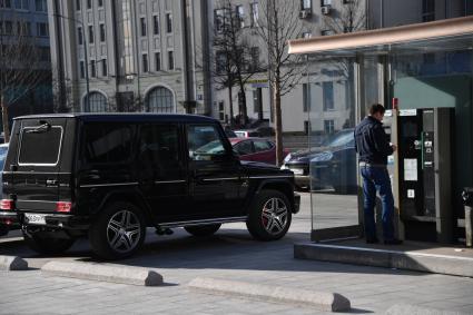 Москва.  Мужчина оплачивает парковку в терминале.