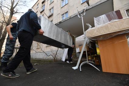 Москва. Мужчины выносят вещи из подъезда дома на Полярной улице.